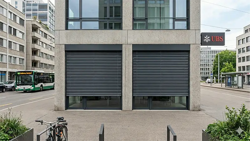 Sicherheitsrollladen an Bürogebäude in der Stadt – Einbruchschutz für Gewerbe, Wälty Storen AG