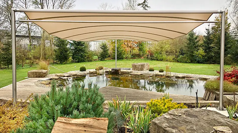 Beiges Sonnensegel über Gartenteich mit Sitzbereich – moderne Beschattungslösung